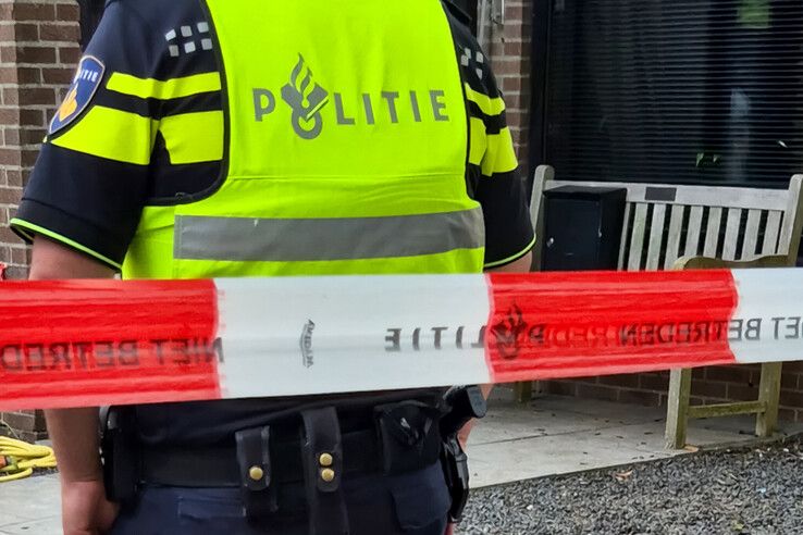 De afgezette achtertuin bij de woning in Genemuiden wordt bewaakt door een agent.