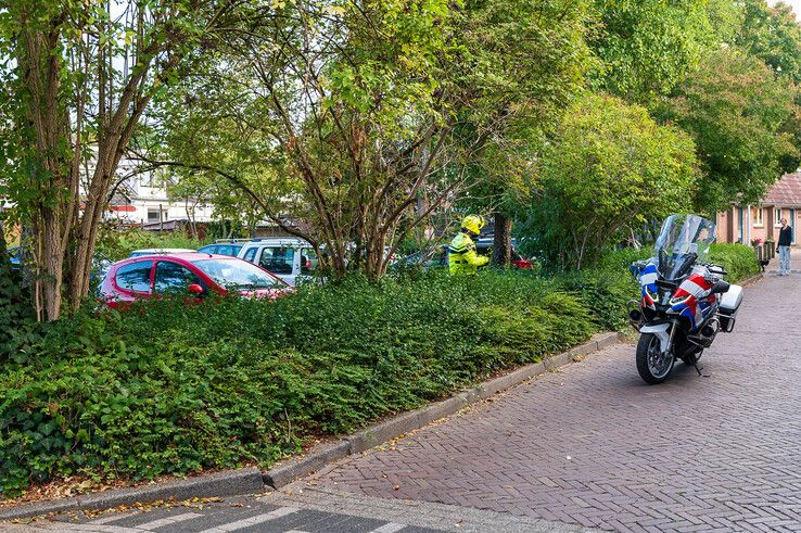 Agent op zoek naar een rode auto in de wijk.