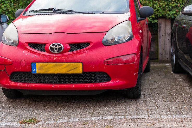 De rode auto met het ontbrekende klepje in de bumper (rechts).