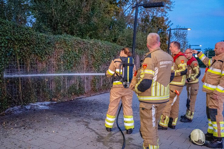 Een brandweervrouw blust de heg op station Kampen.