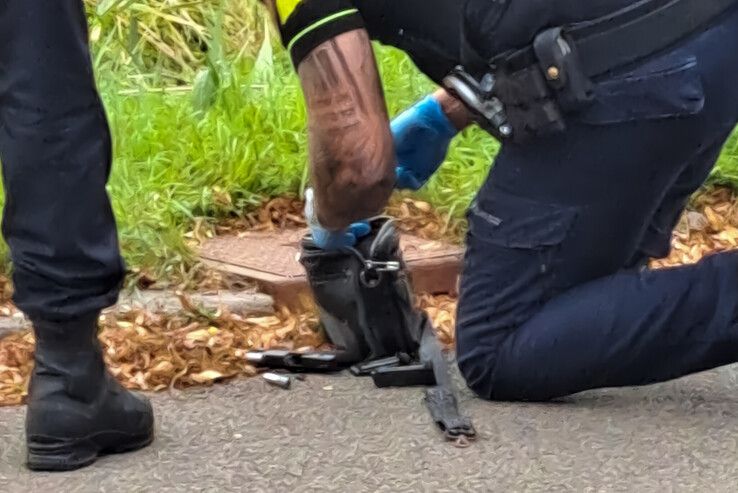 Een politieman onderzoekt de tas met wapen aan de Diasporalaan in Zwolle.