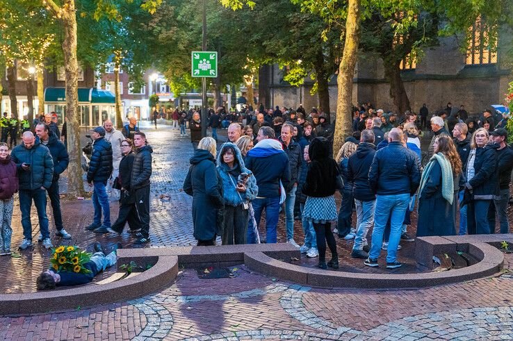 Tegendemonstrant ligt met bloemen op het plein.