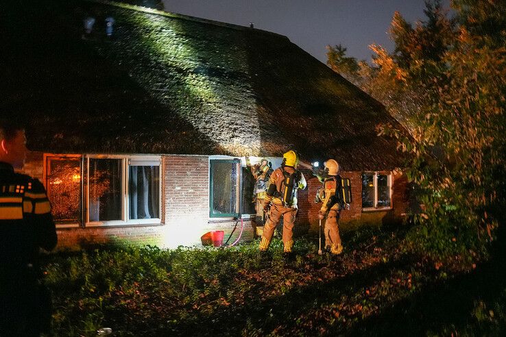 Brandweerlieden inspecteren het rieten dak bij Trias Jeugdhulp.