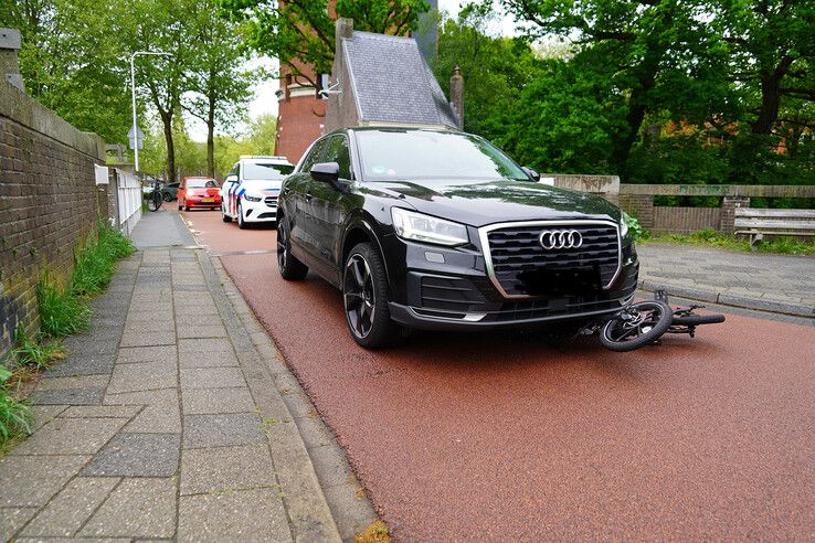 Jonge man onderuit op vouwfiets en onder auto terecht